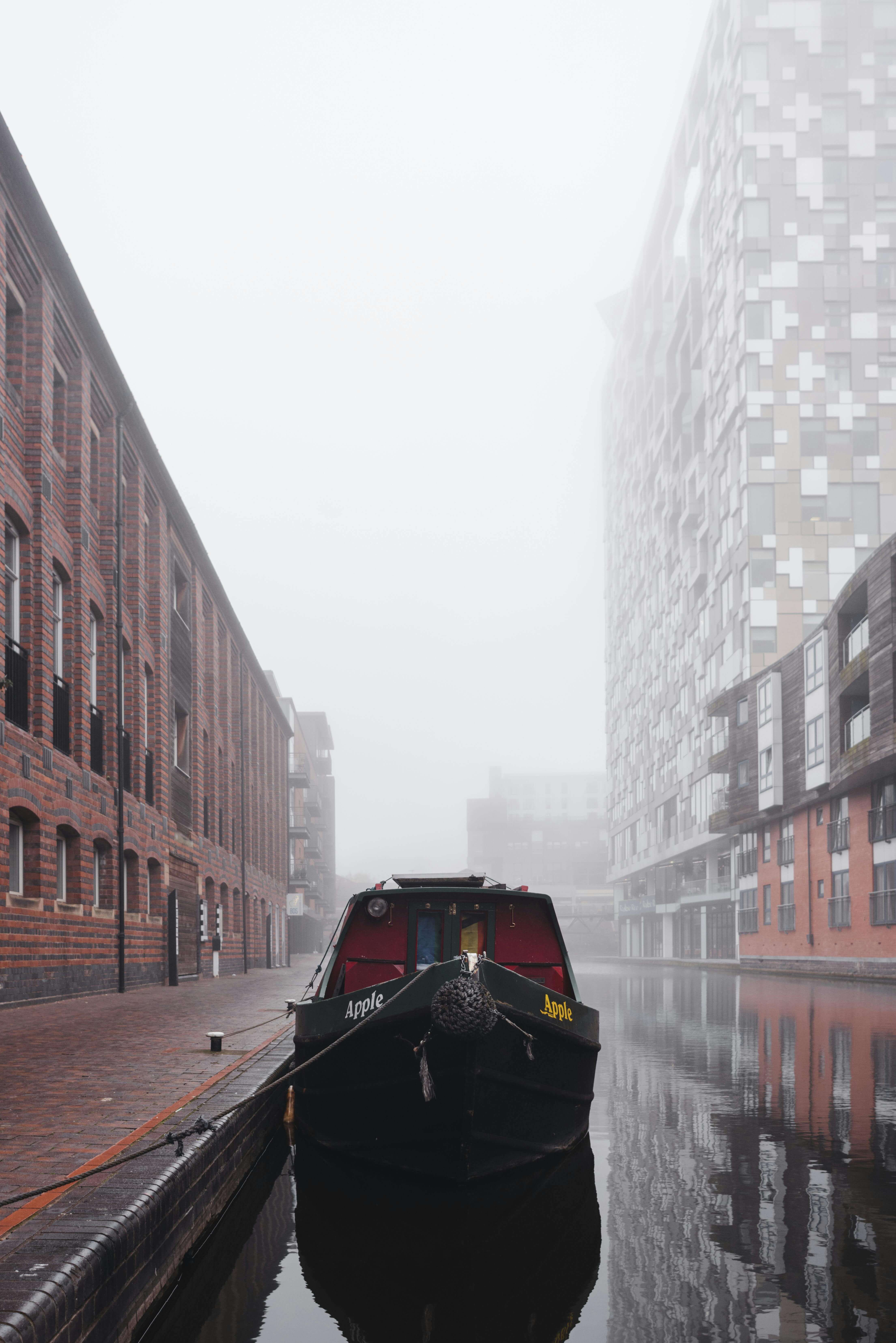 Narrowboat moored on Birmingham canal with Victorian warehouses in morning mist