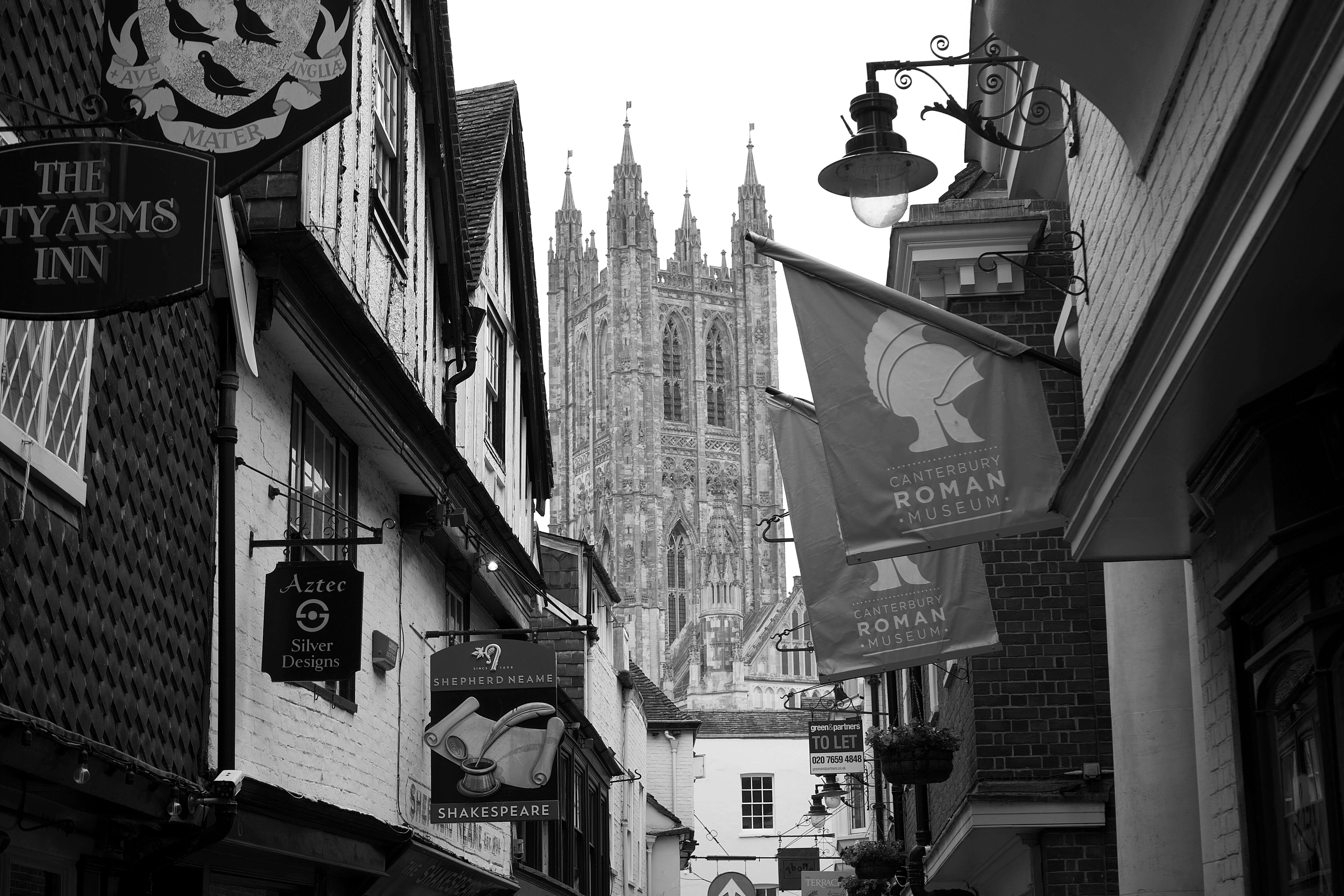 Canterbury Cathedral bell tower rising above historic narrow street with shops and pubs