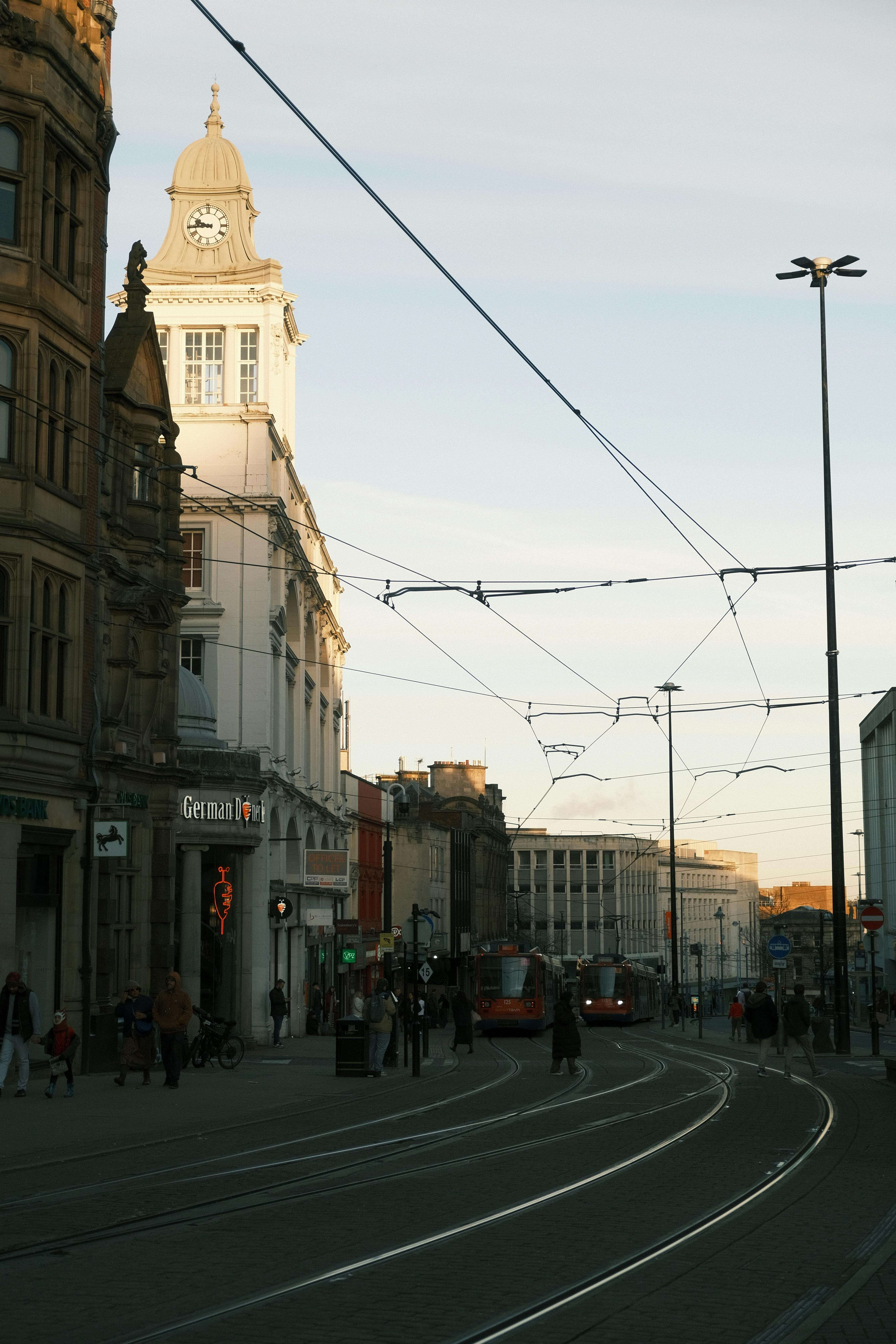 Sheffield city centre with tram lines and Town Hall clock tower at dusk